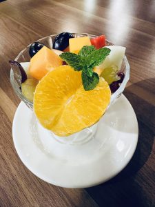 A glass filled with assorted fresh fruit dessert. 