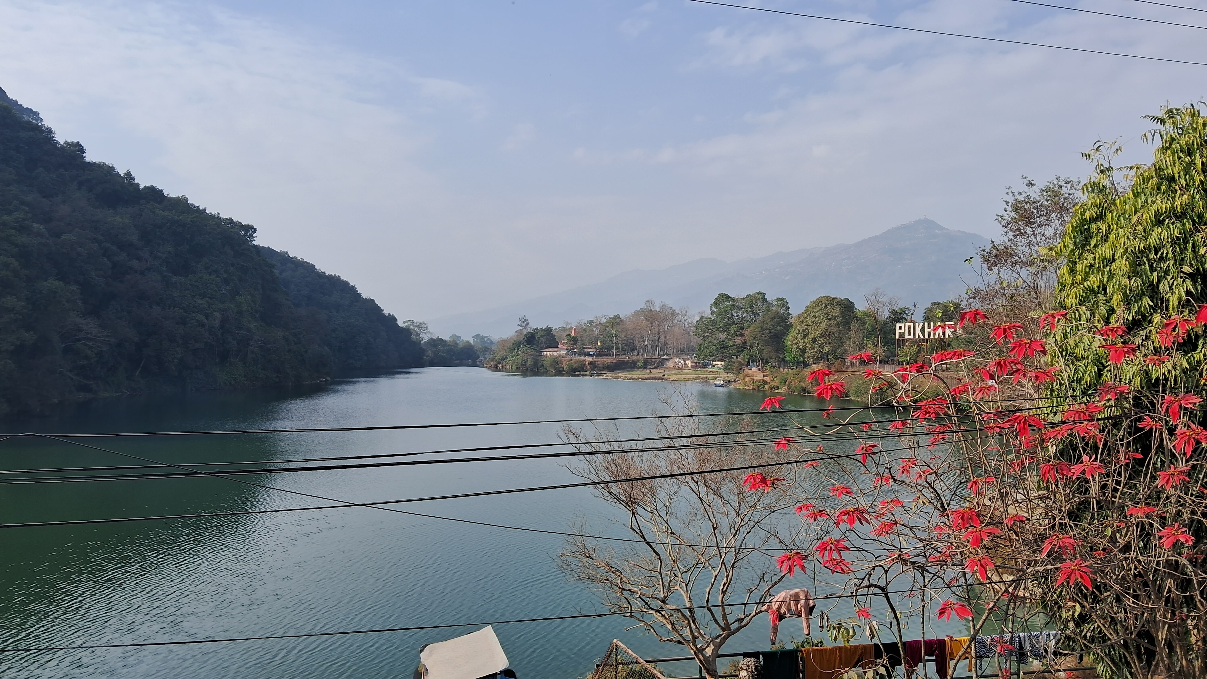 A serene lake surrounded by lush green hills under a partly cloudy sky.