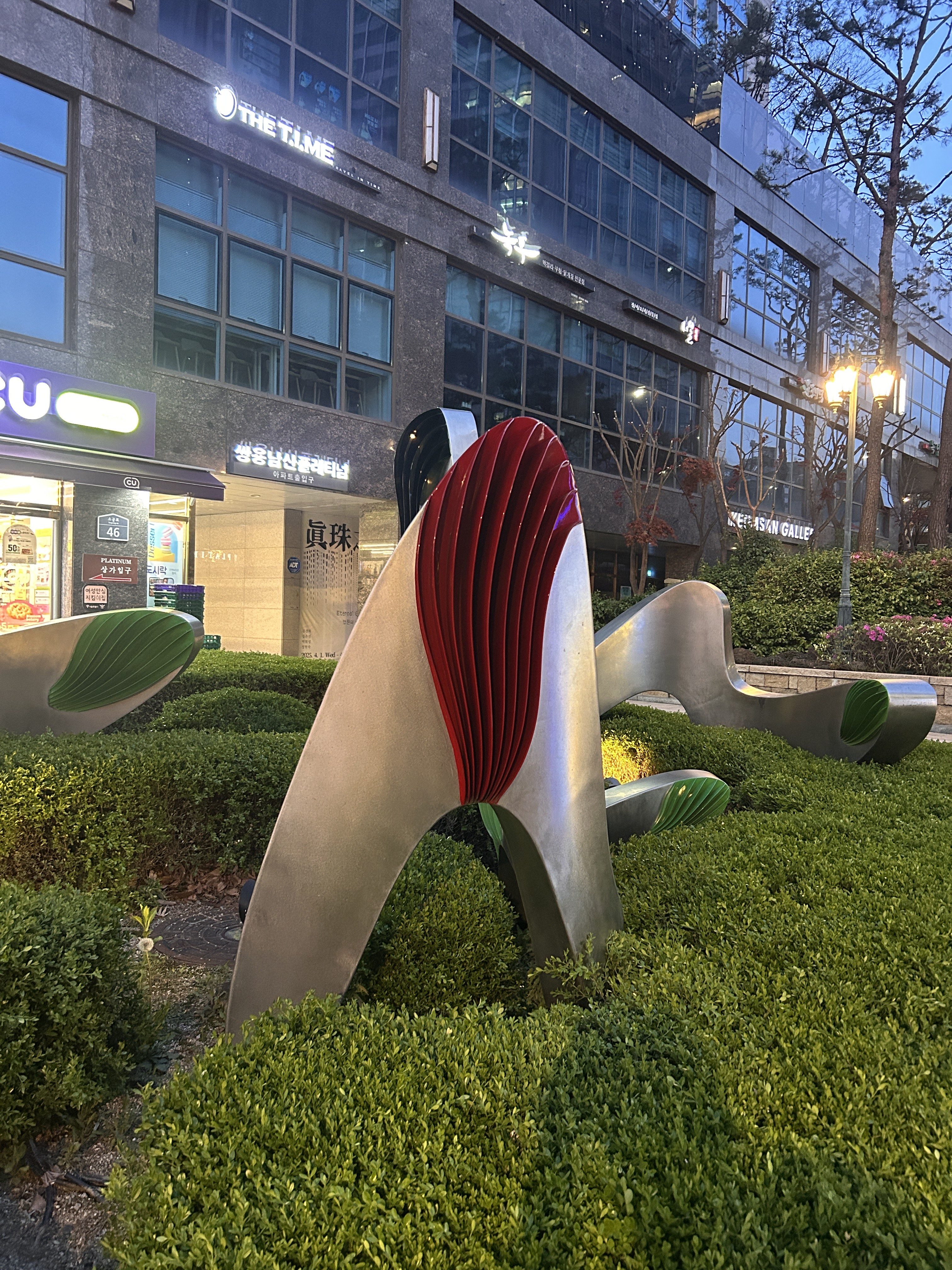 A modern abstract sculpture made of metal with curved and flowing shapes, featuring bright red and green elements.