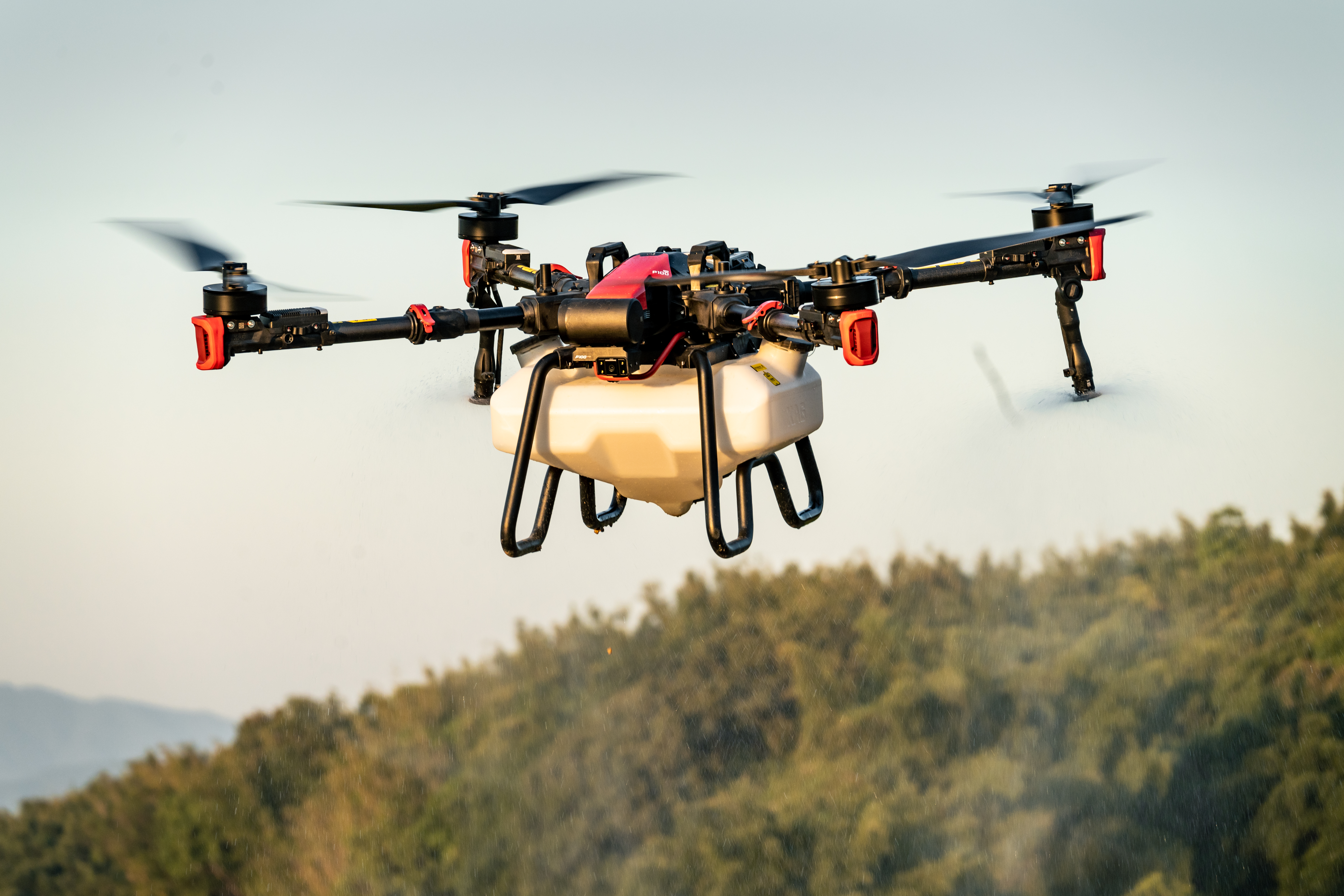 A close-up of a drone in flight with hills in the background.