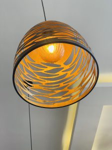 A hanging ceiling lamp with a decorative orange and black perforated shade, casting a warm glow.