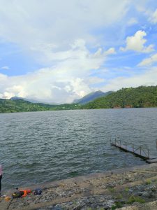 
A scenic view of a large begnas lake with gentle waves under a partly cloudy sky