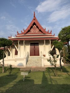 A white and red traditional temple with intricate roof designs, set against a blue sky.