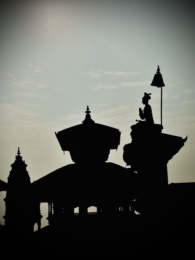 The statue of King Bhupatendra Malla and traditional pagoda-style temples at Bhaktapur Durbar Square.