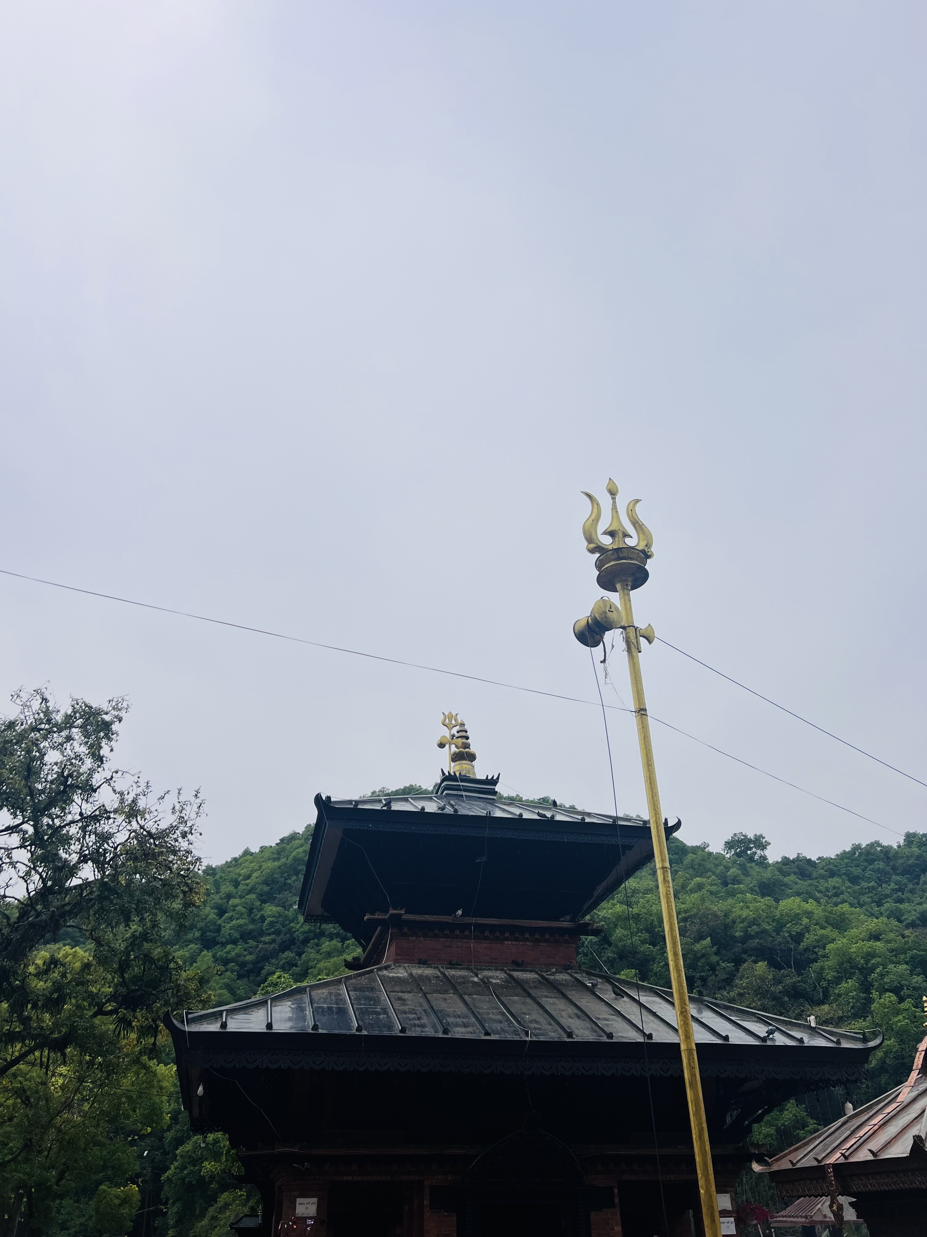 A traditional temple structure with a multi-tiered roof is shown in the foreground, featuring intricate designs and a distinct finial at the top.