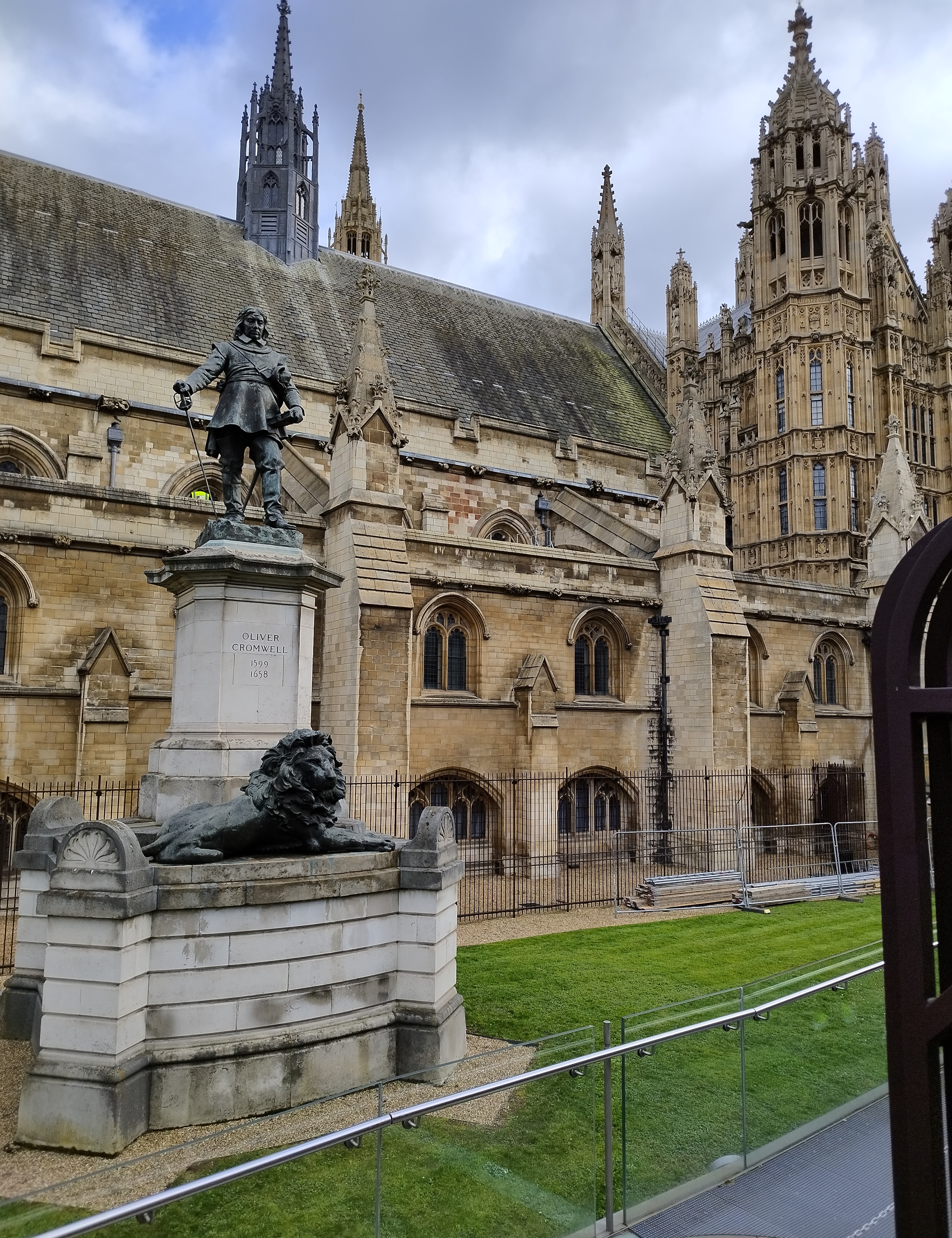 A statue of a historical figure stands on a pedestal beside a reclining lion sculpture