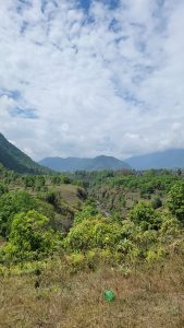 A scenic landscape featuring lush green hills and valleys under a partly cloudy sky. 