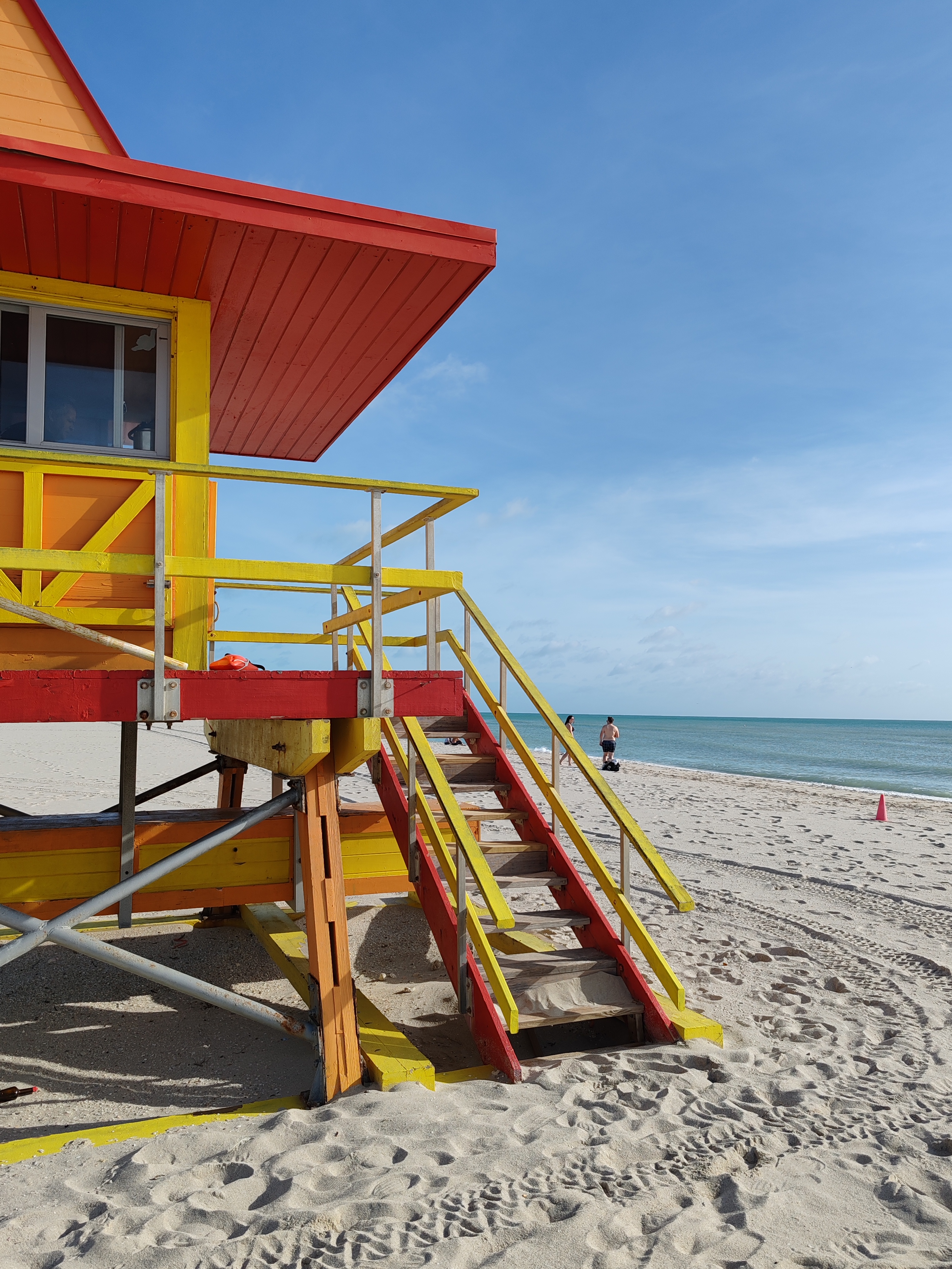A colorful lifeguard station with red, yellow, and orange accents on a sandy beach