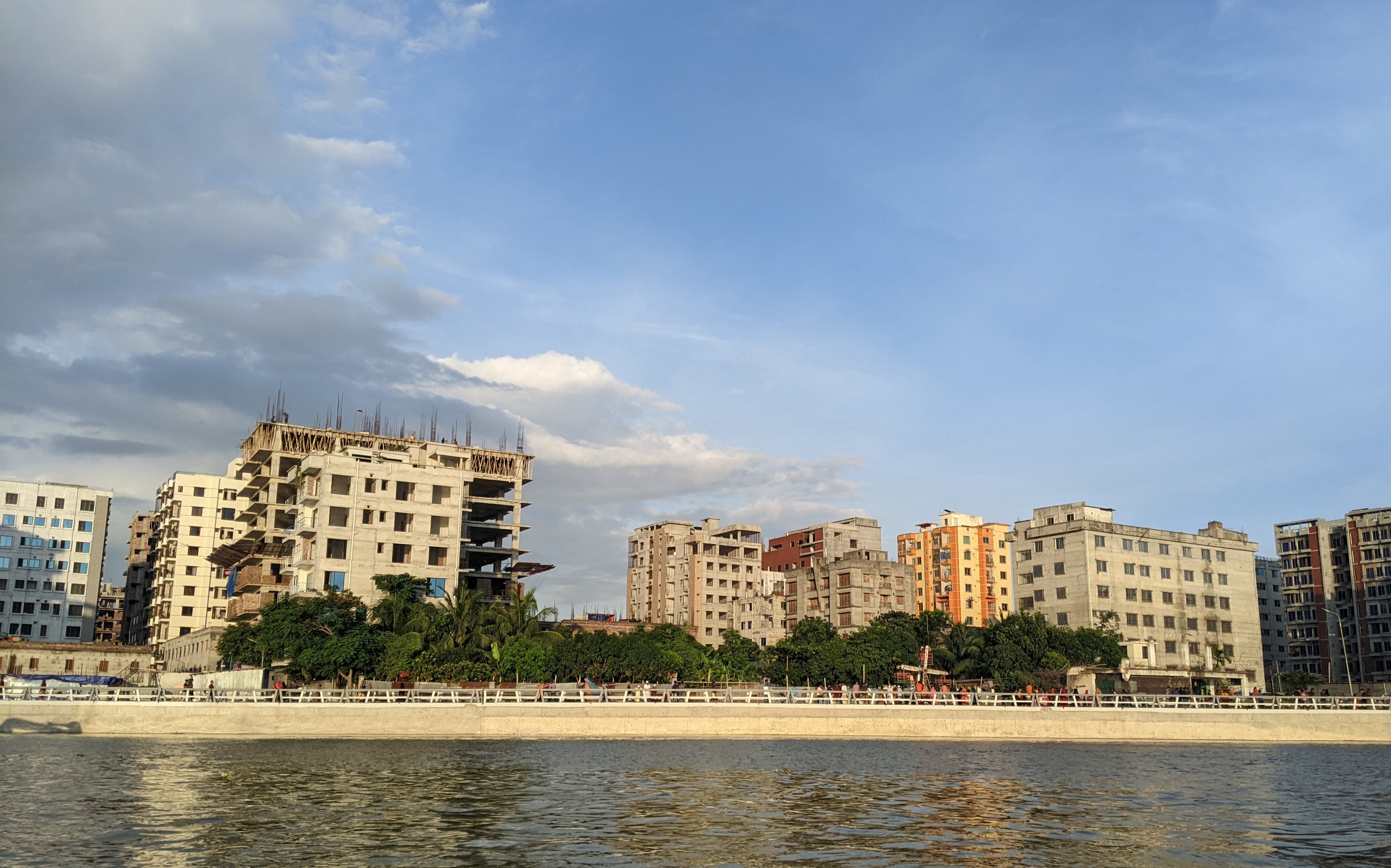 A scenic view of an urban riverfront with several multi-story buildings under construction or completed.