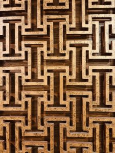 Intricate geometric wooden lattice design with interlocking patterns carved in light brown wood. 