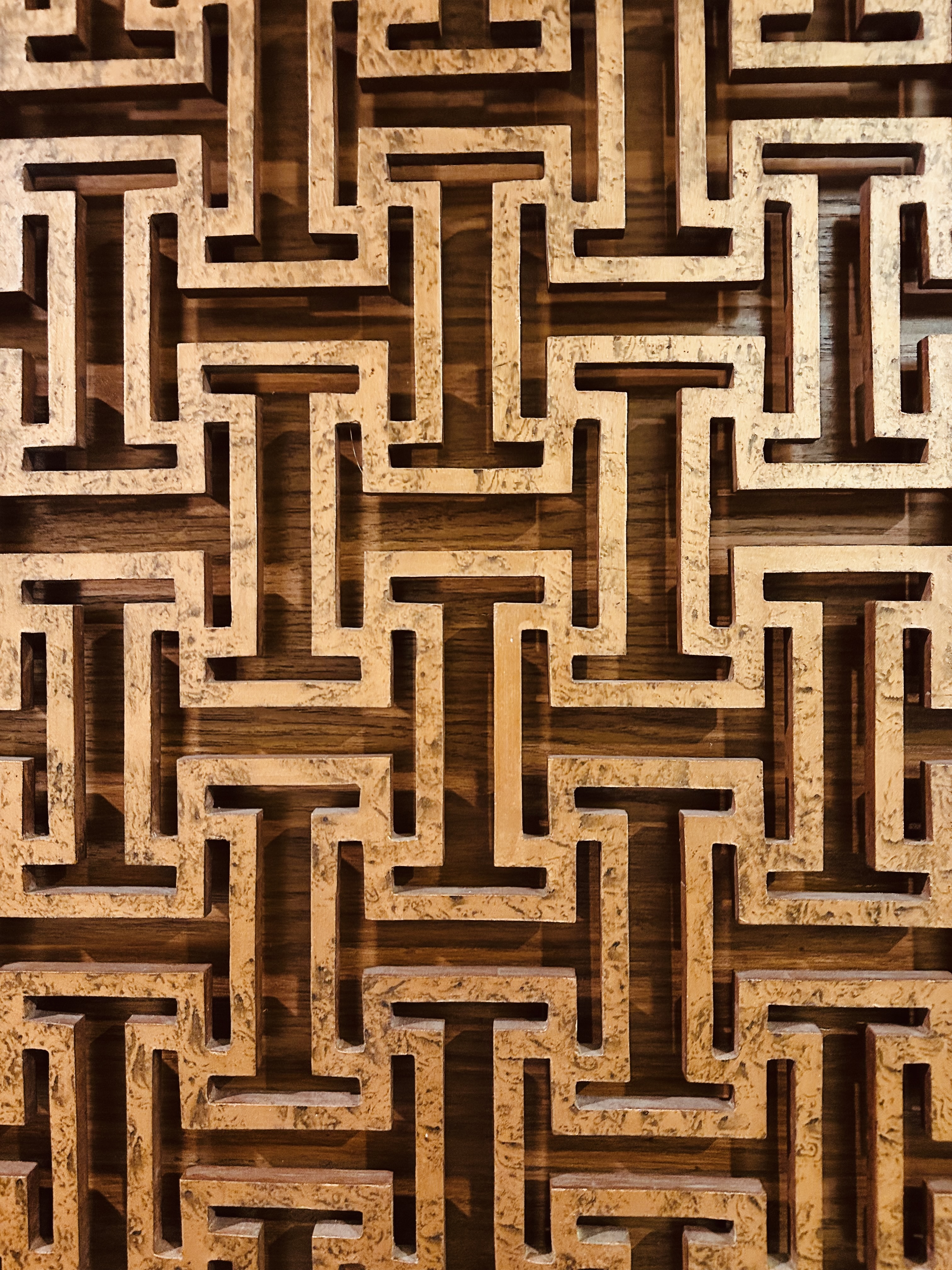 Intricate geometric wooden lattice design with interlocking patterns carved in light brown wood.
