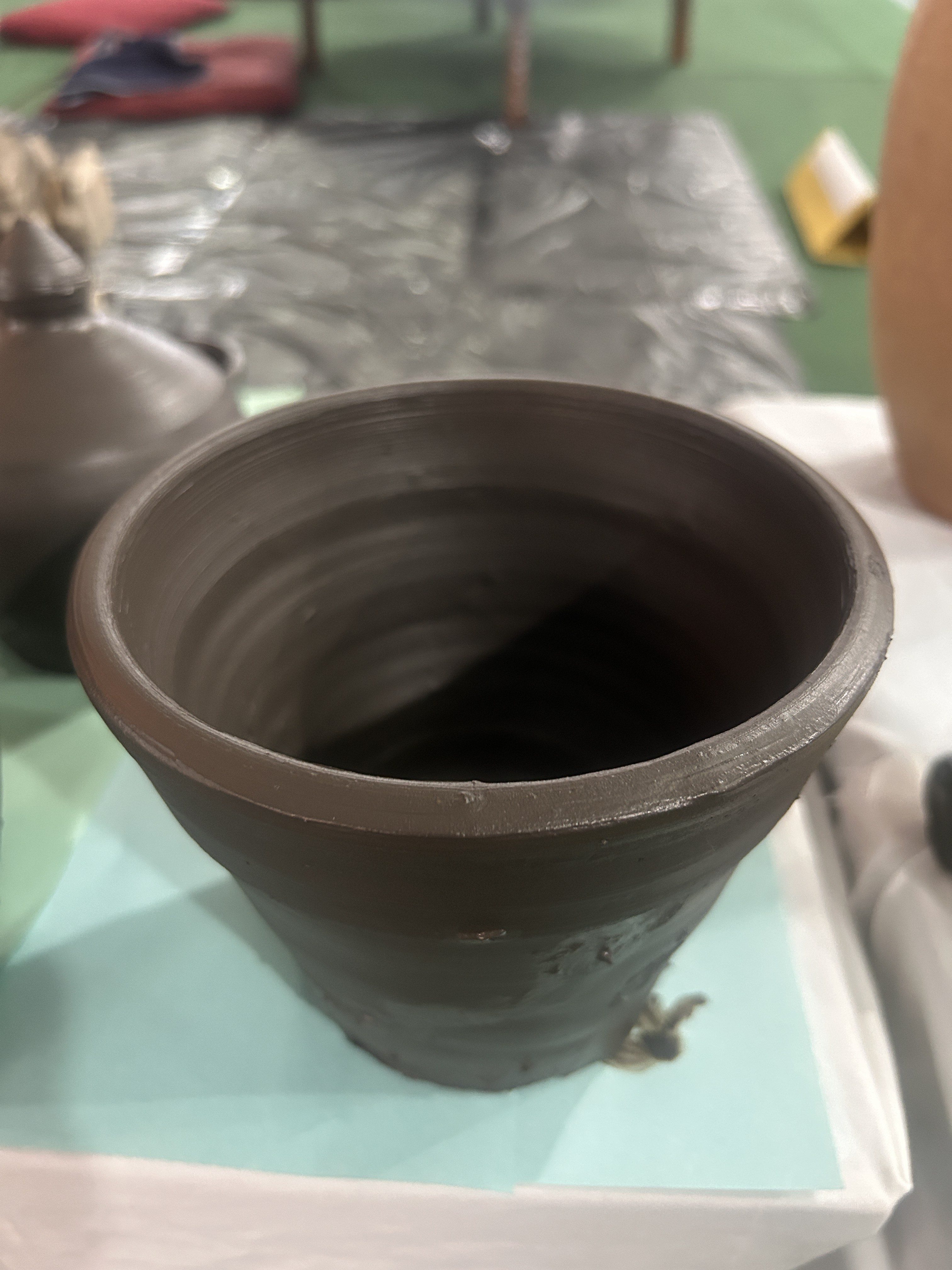 A hand-thrown clay pot placed on a table with a blurred background.