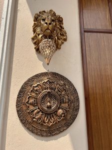 A decorative wall with a sculpted lion head and a hanging crystal ornament underneath it.