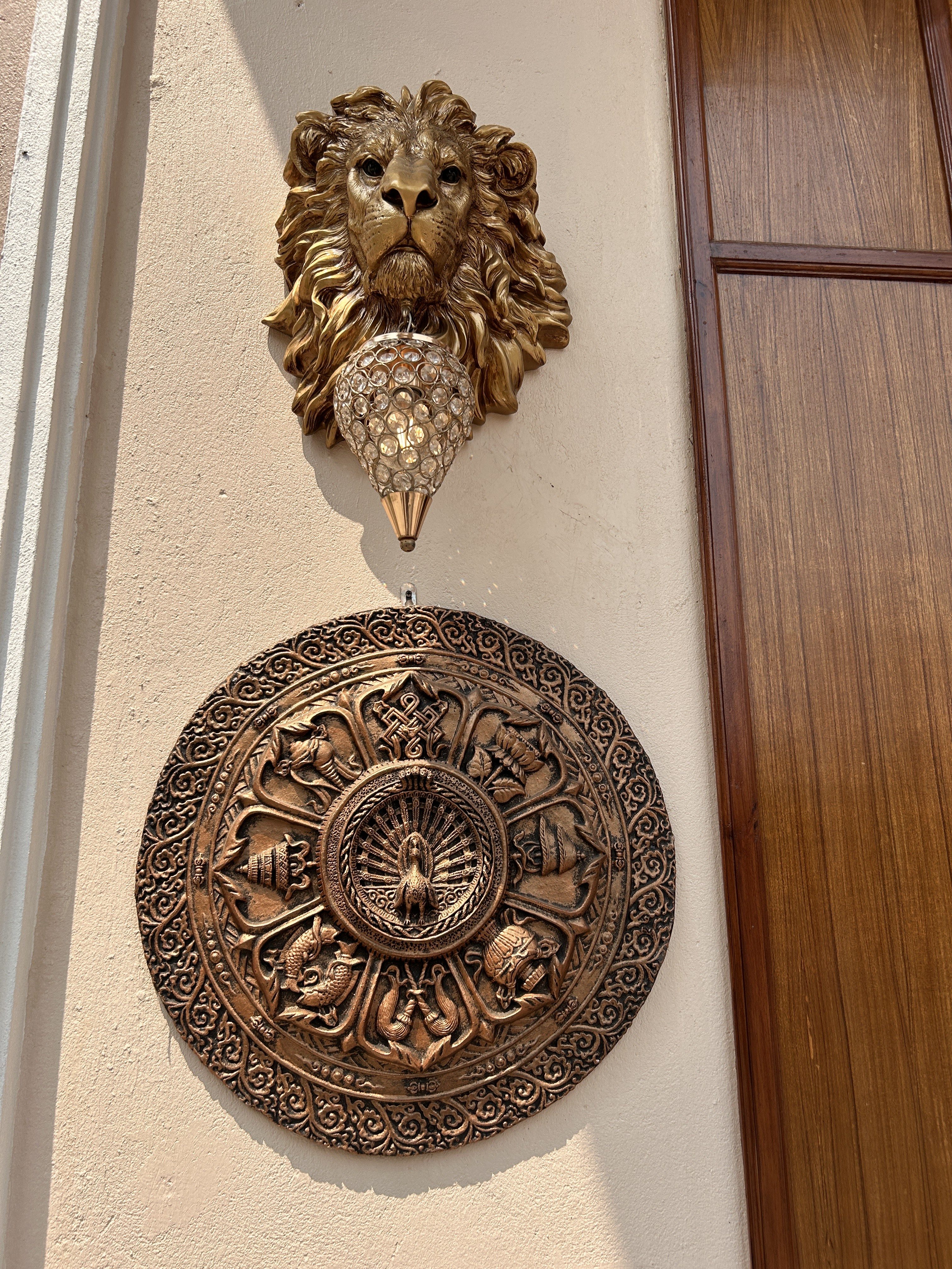 A decorative wall with a sculpted lion head and a hanging crystal ornament underneath it.