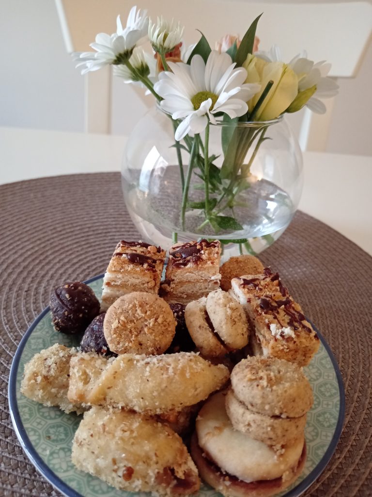 A round plate filled with an assortment of sweet pastries and desserts, including cookies, chocolate-covered treats, and layered cakes