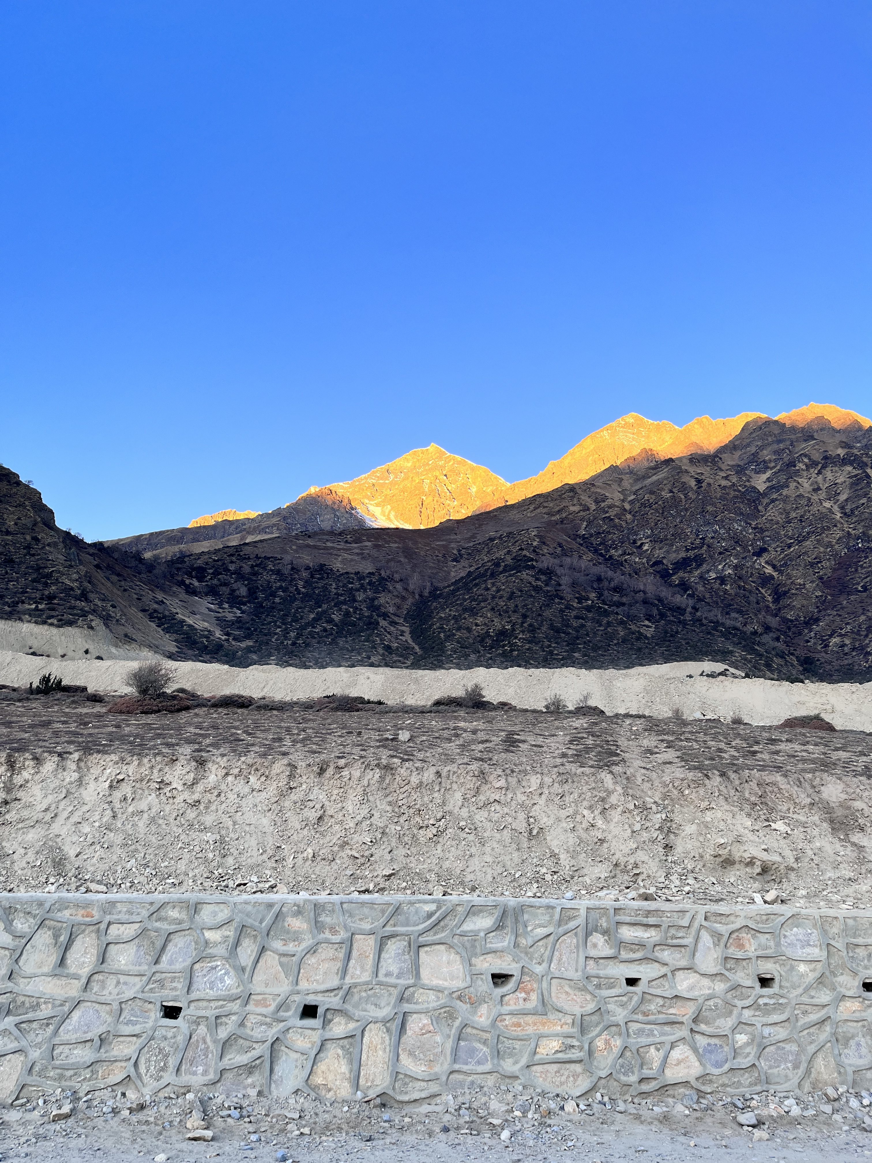 A panoramic view of rugged mountains under a clear blue sky.