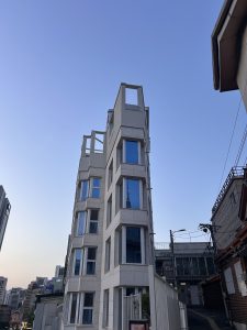 A modern building with a unique architectural design featuring multiple windows and an unfinished roof structure.