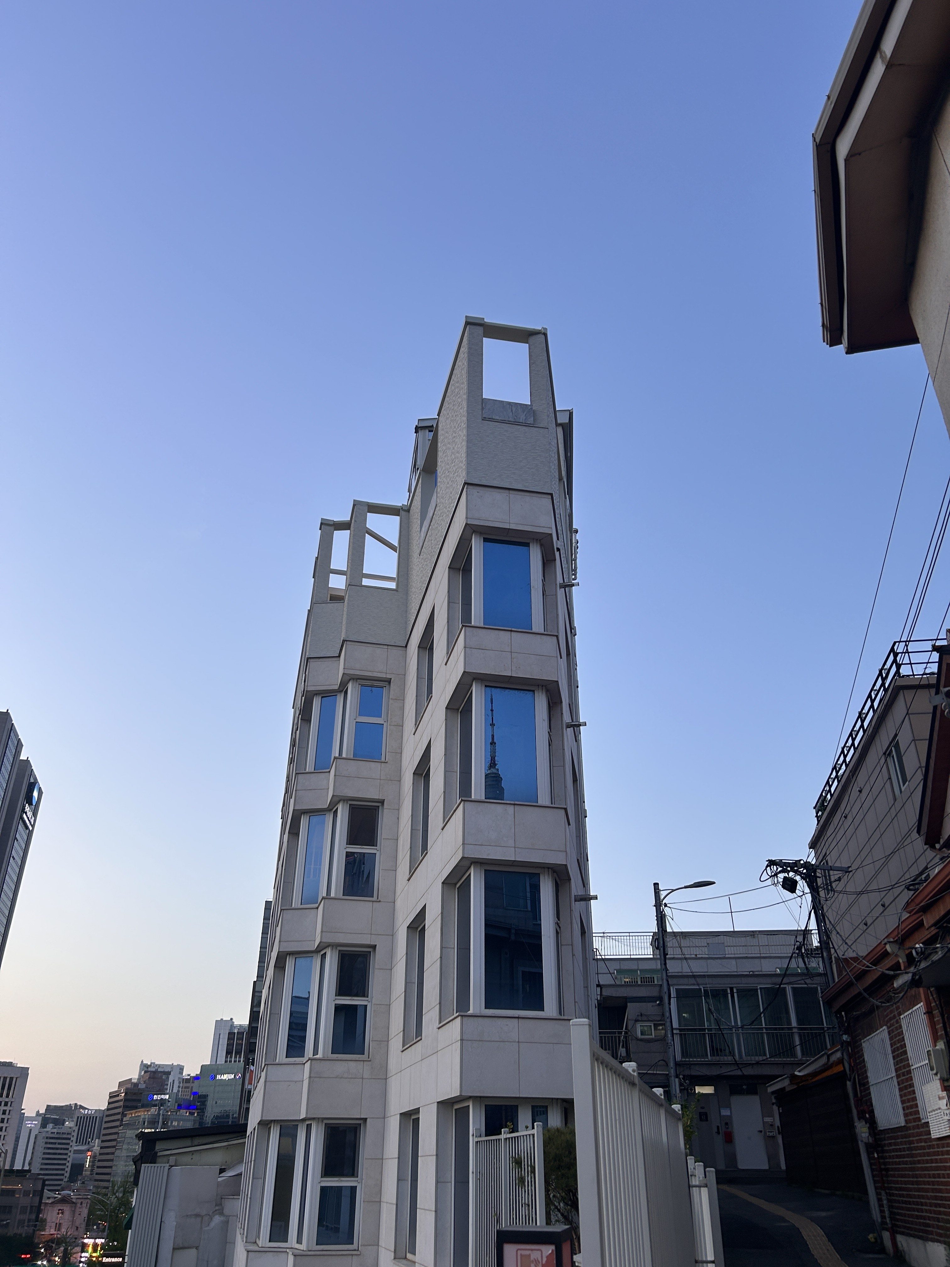 A modern building with a unique architectural design featuring multiple windows and an unfinished roof structure.