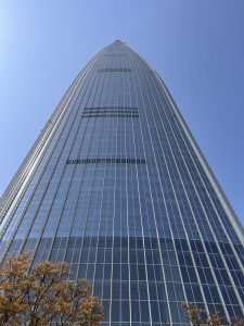 A tall, modern lotte tower with a sleek, glass facade rises sharply against a clear blue sky.