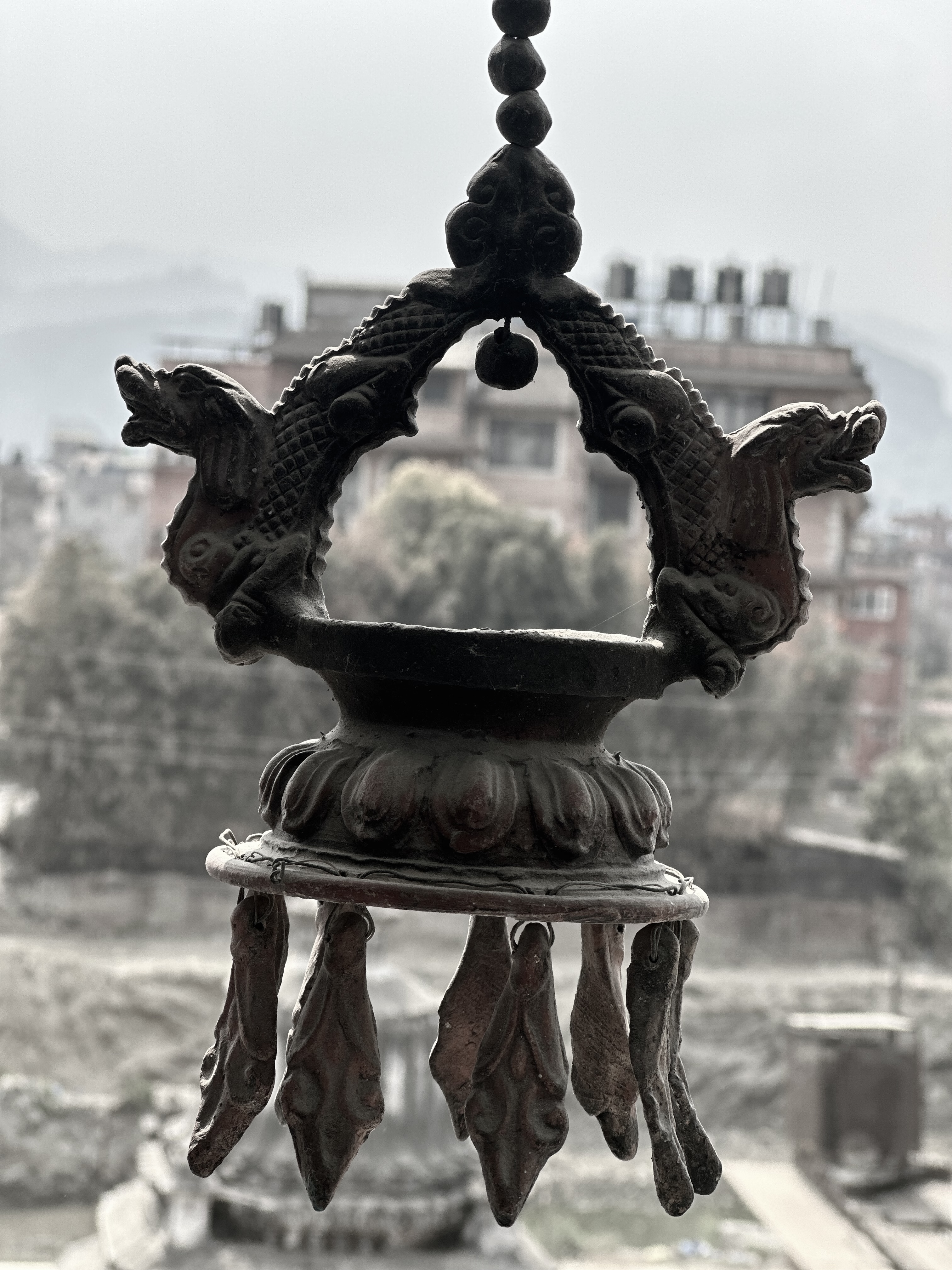 An ornate metal hanging lamp with dragon motifs and decorative tassels.