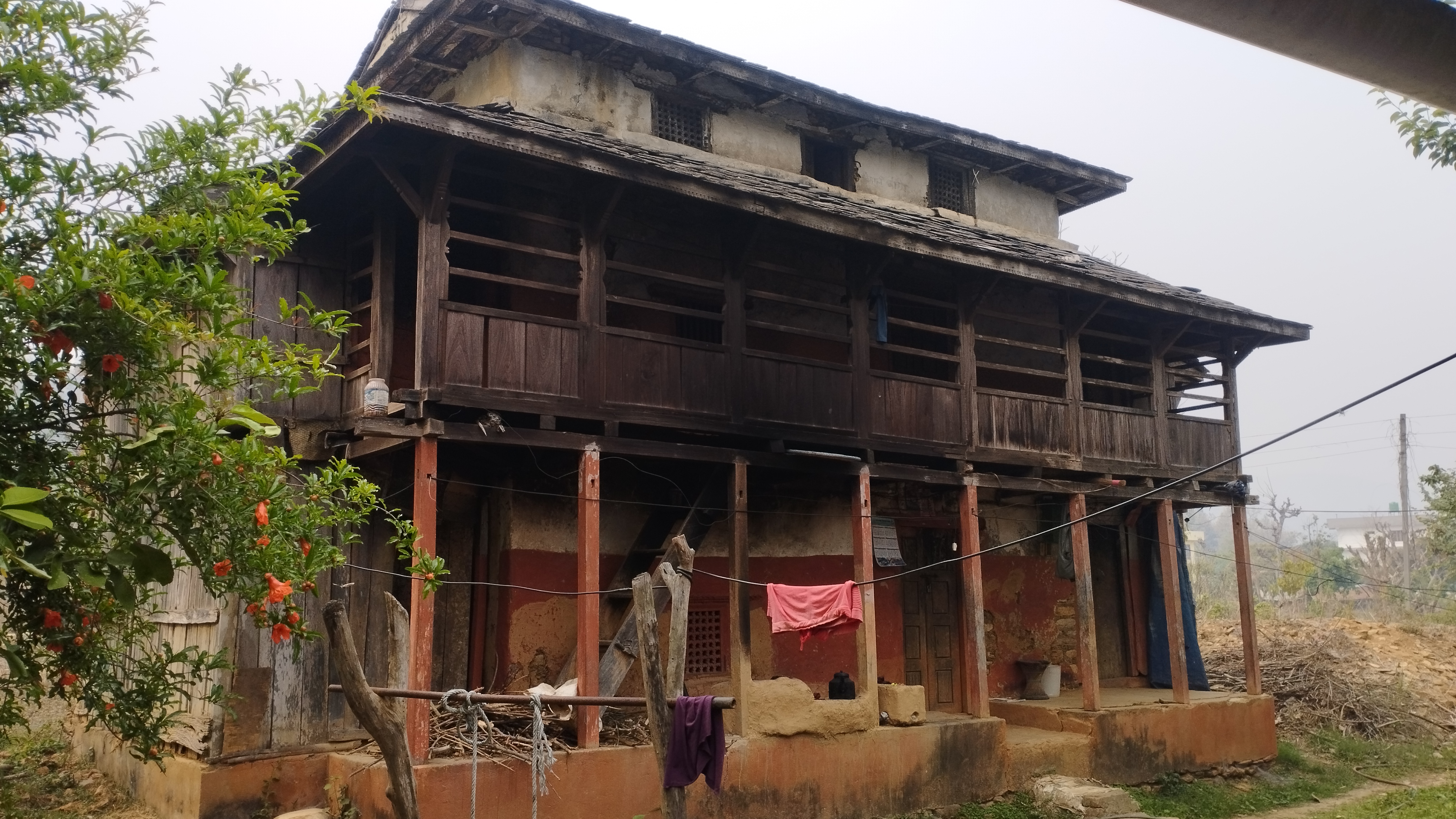 An old, two-story house with wooden and stone construction, featuring a covered balcony.