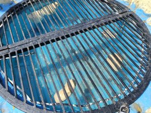A circular metal grate covers an opening in a blue container, through which several light-colored spheres are visible in the water below.