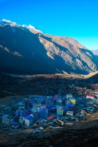 A colorful village nestled in a mountainous landscape, with buildings of various bright colors at the base of a large mountain