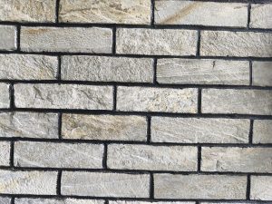 A close-up view of a stone brick wall with rectangular blocks arranged in a horizontal pattern.