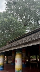 A traditional structure with a thatched roof supported by colorful columns painted with floral designs and patterns.