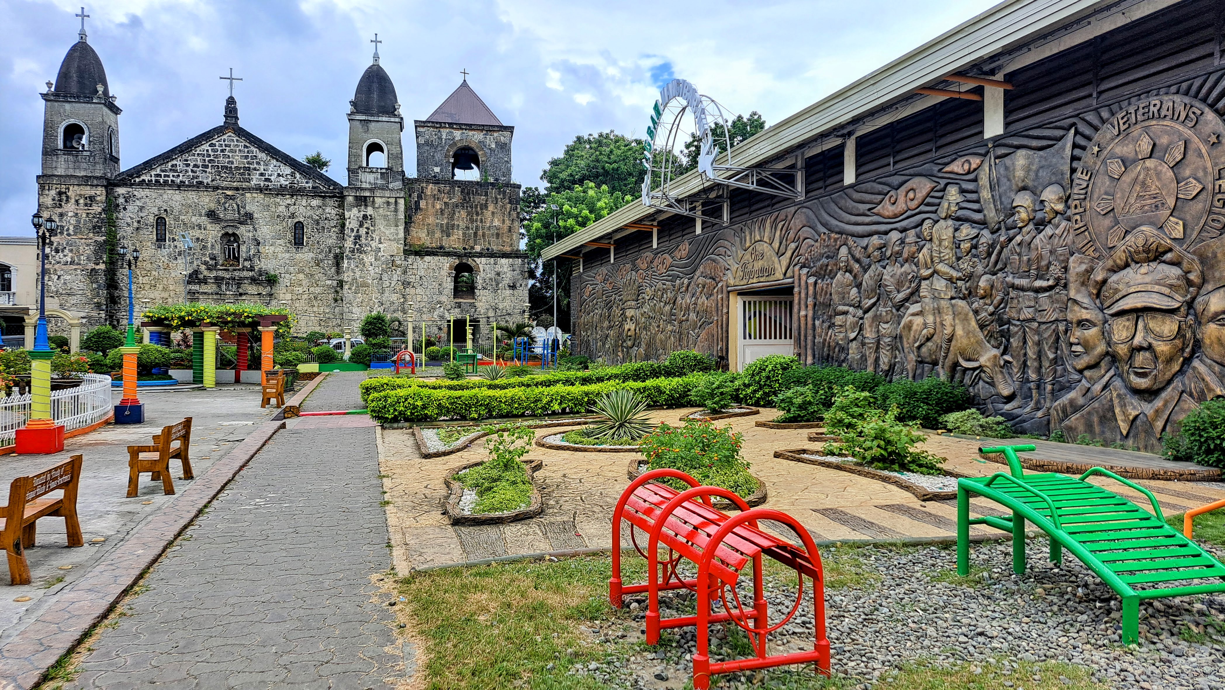 Mural wall depecting a local tradition with a centuries old church, surrounded with small landscaped garden and children's playground.