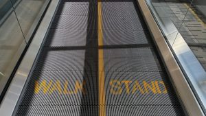 The surface of a moving sidewalk, the left side labeled "Walk" and the right side labeled "Stand".