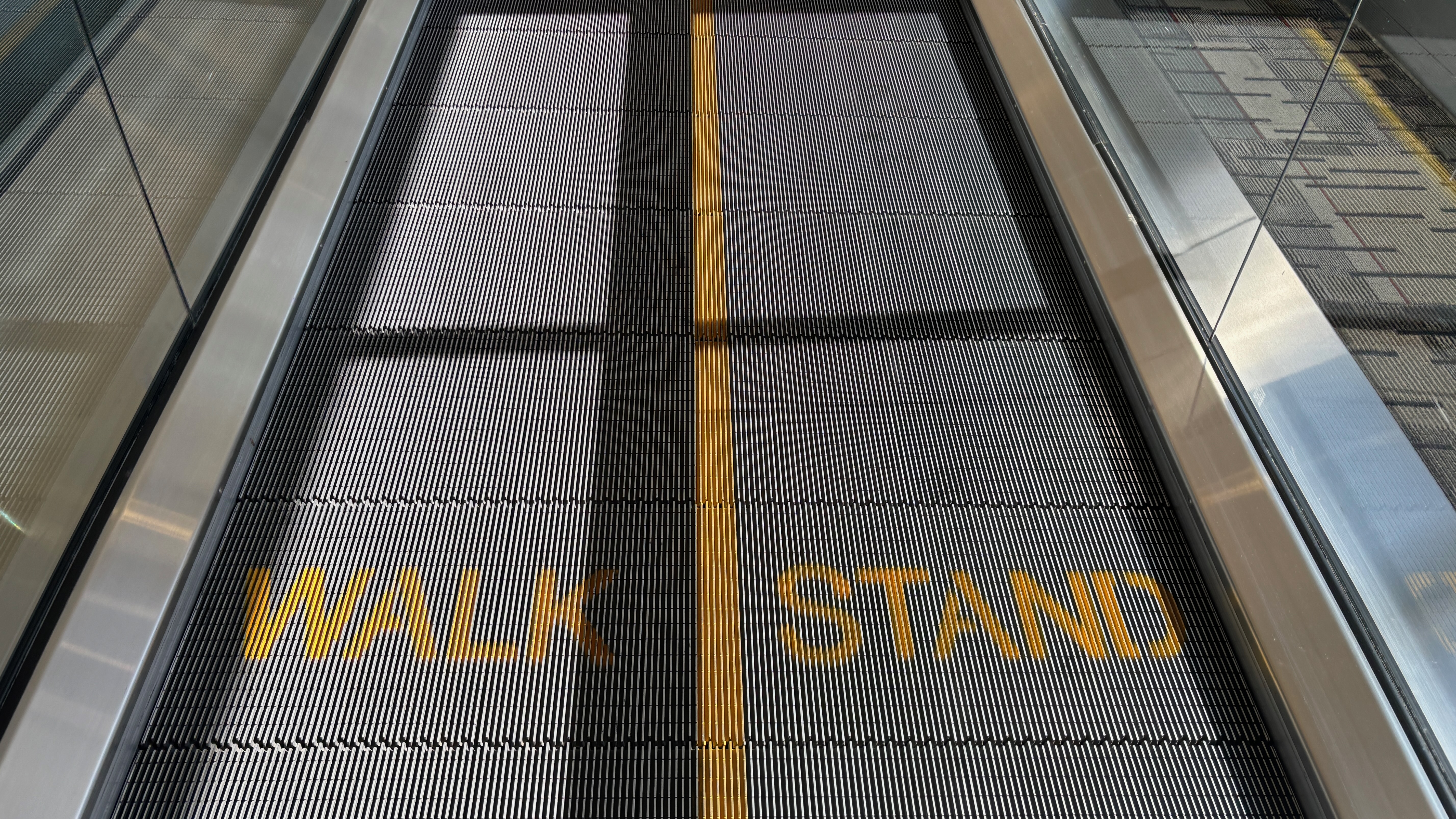 The surface of a moving sidewalk, the left side labeled "Walk" and the right side labeled "Stand".