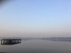 Serene early morning view of a calm lake with an ancient stone pavilion structure partially submerged in the water. 