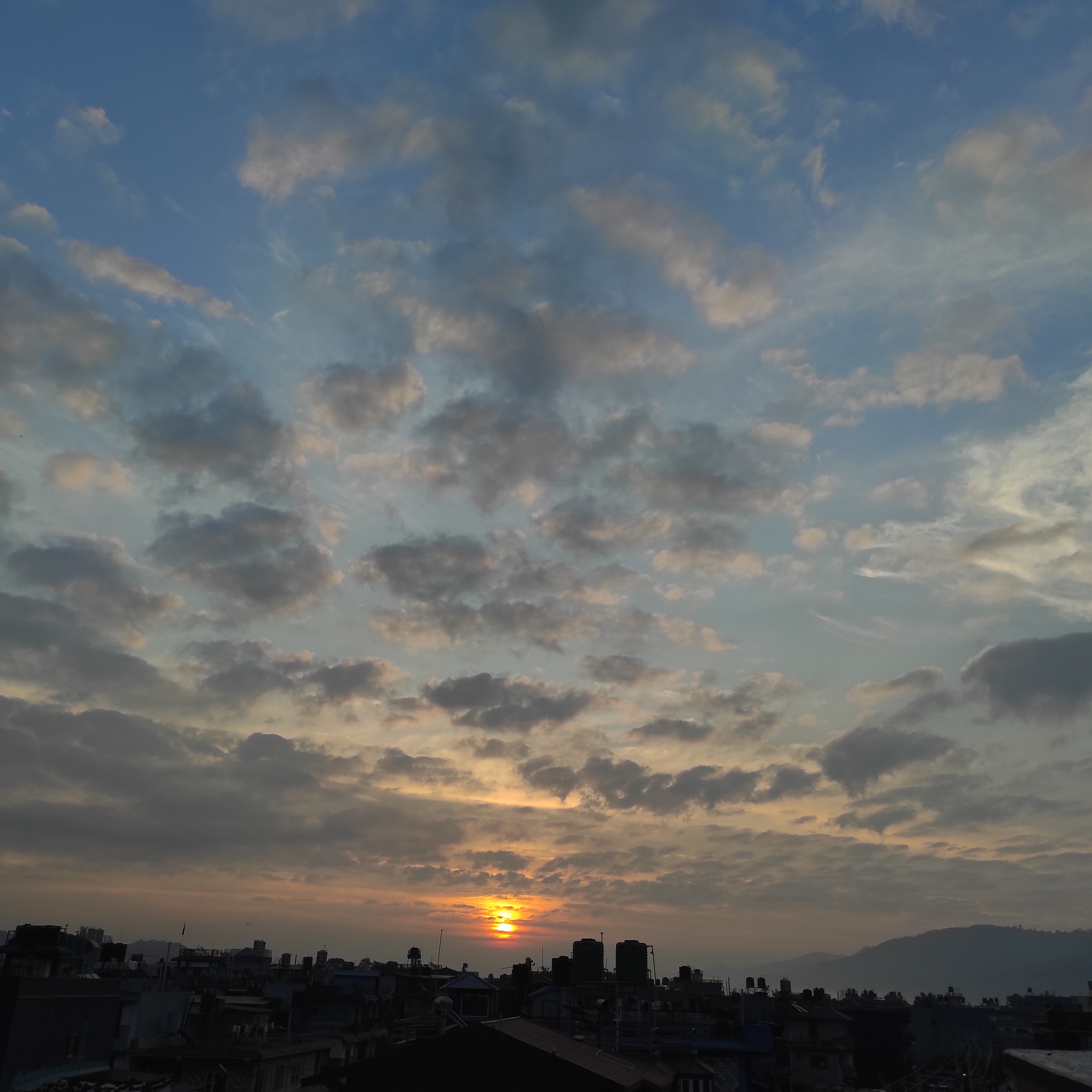 A scenic view of a sunset behind a city skyline, with a gradient sky displaying shades of blue and orange.