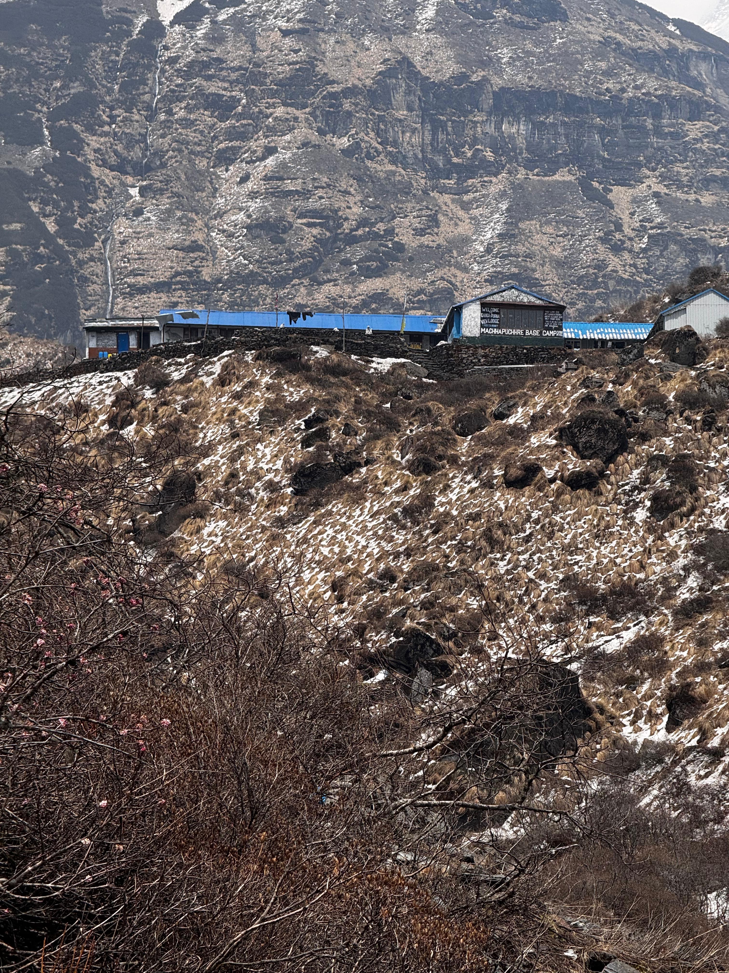 A mountainous landscape featuring rugged terrain and a few buildings with blue roofs situated on a ridge.