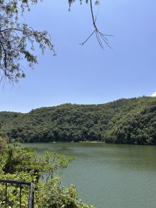A serene view of a Fewa lake surrounded by lush green hills under a clear blue sky. 