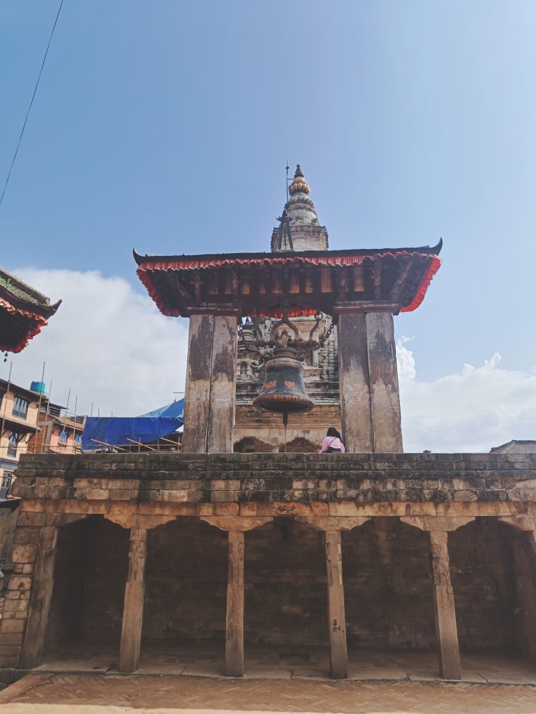 A traditional architectural structure featuring a large bell hanging beneath a roofed pavilion.