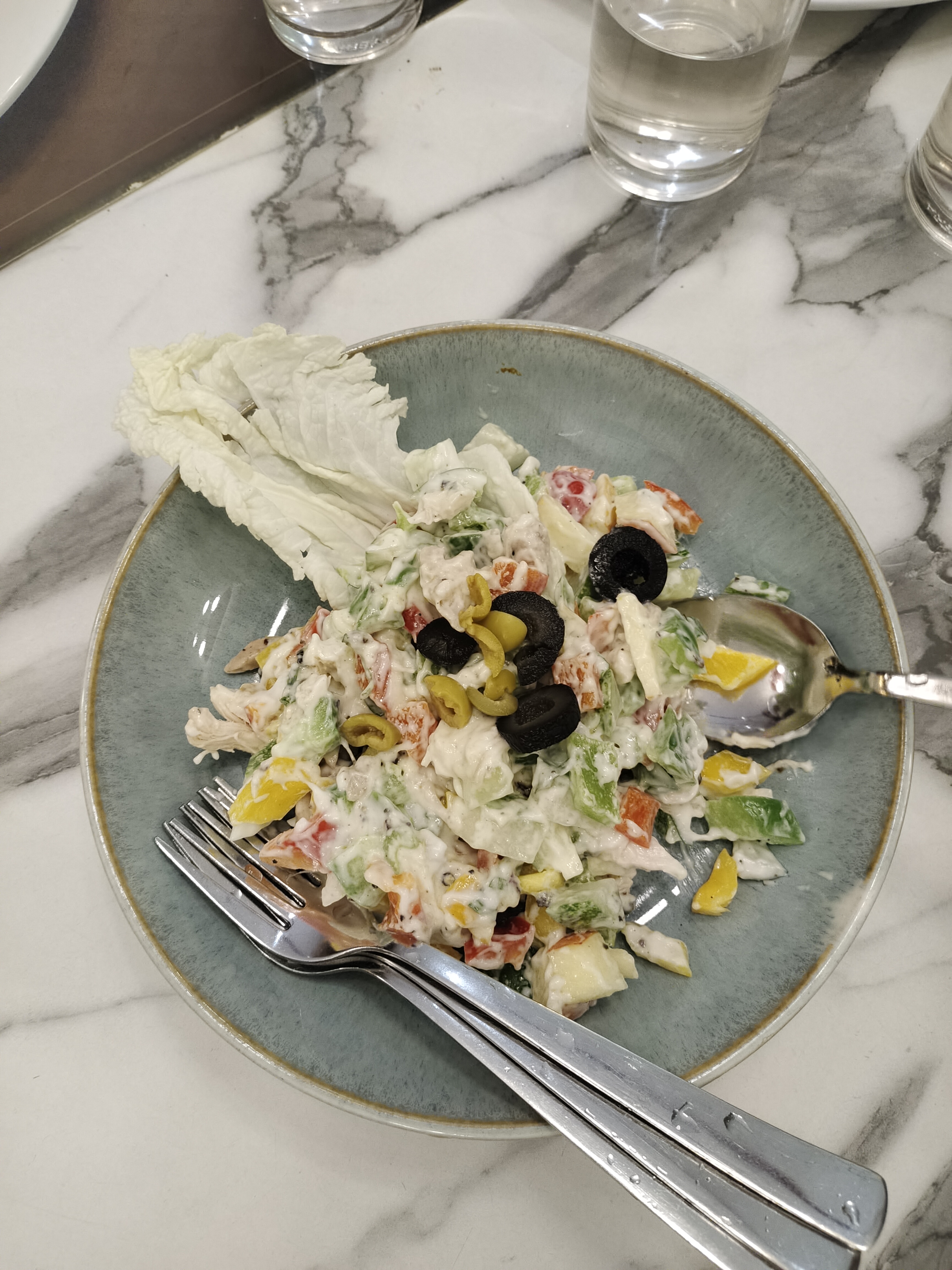 A serving of mixed chicken salad is presented on a round, light blue plate with a gold rim.