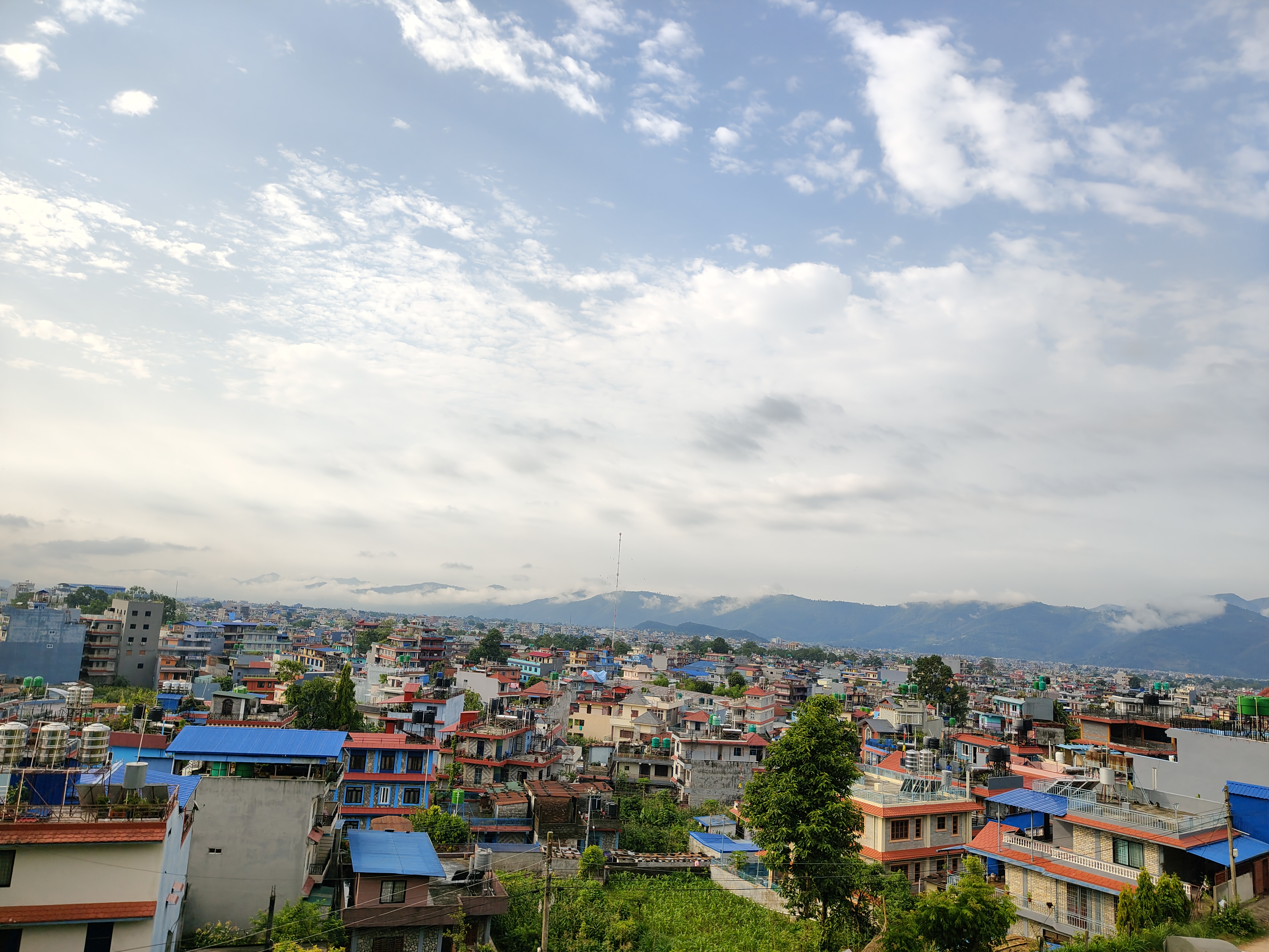 A panoramic view of a colorful urban landscape, featuring a dense arrangement of buildings with various roof colors including blue, red, and gray.