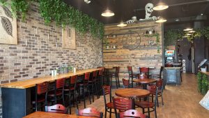 The seating area of a coffee shop with a giant skeleton climbing over the wall.