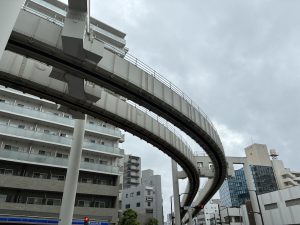 

A view of a modern elevated monorail track curving through an urban environment, with tall buildings in the background. 