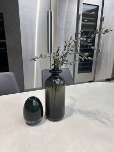 A modern kitchen scene featuring two glass vases on a light-colored countertop. 