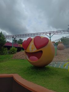 A large, round sculpture resembling a cartoonish emoji with a big smile, heart-shaped eyes, and a cheerful expression.