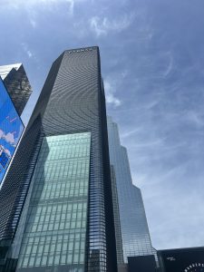 A tall, modern skyscraper reaches upward against a clear blue sky, showcasing a sleek glass and black exterior.