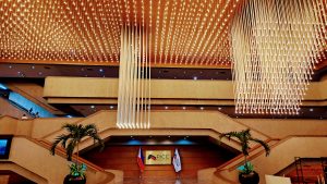 An interior view of a grand event space, featuring a high ceiling adorned with a striking arrangement of lights resembling cascading strands.
