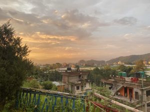 A scenic view of a rural landscape during sunset, showcasing a sky filled with soft, golden hues and scattered clouds.