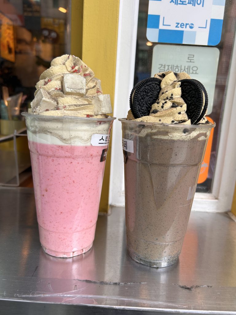 Two large plastic cups filled with blended beverages sit on a metal surface.