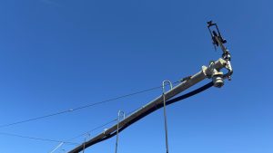 A large sprinkler head from an industrial sized irrigation system.  It's viewed from below with blue sky behind it.