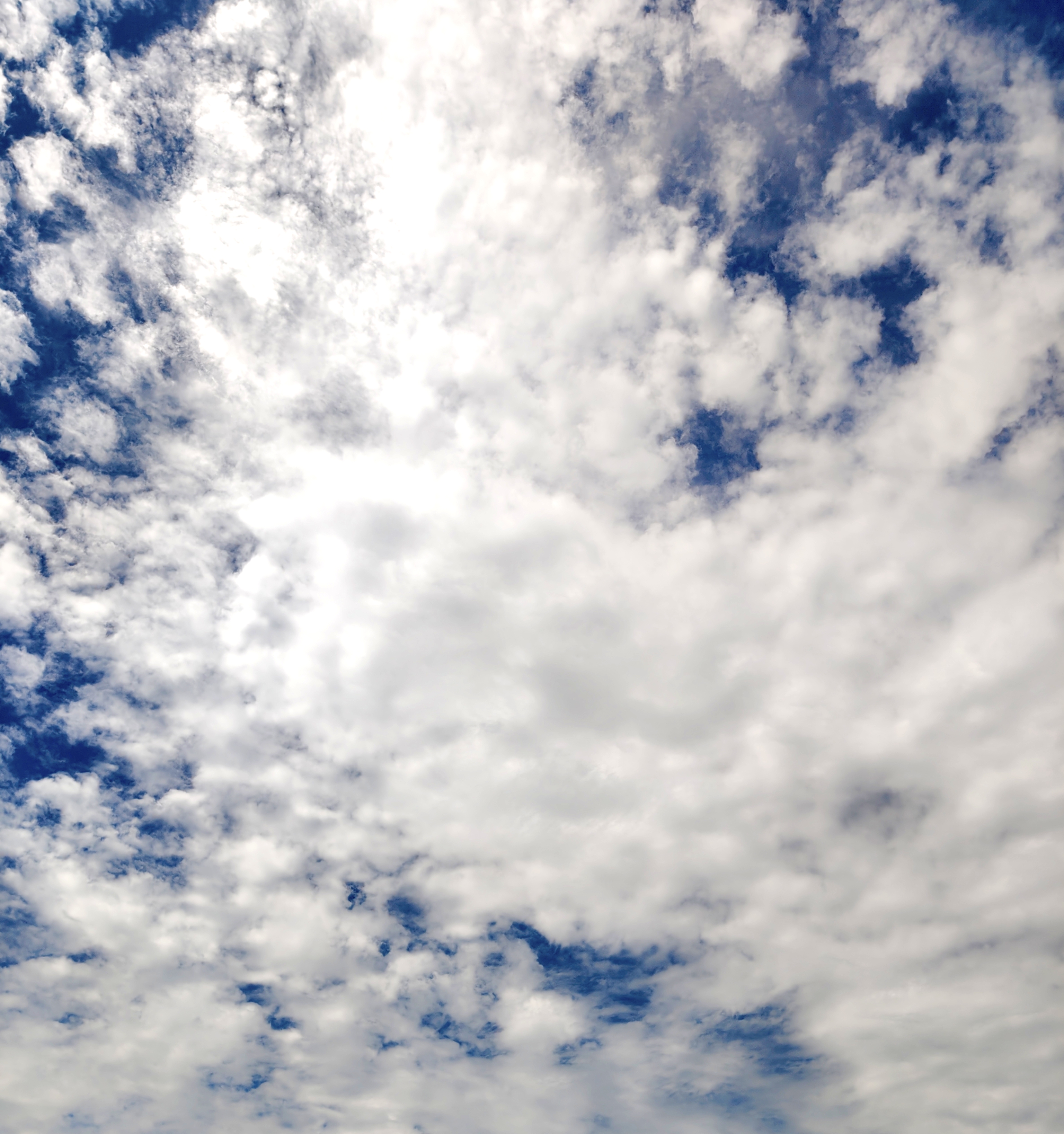 A wide view of the sky filled with a blend of white and gray clouds against a backdrop of deep blue.