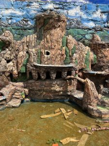 A detailed artificial rock formation depicting a mountainous landscape with a small water pool at the base.
